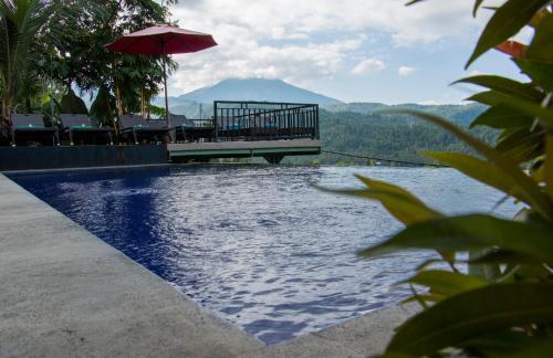 姆杜克巴厘岛拉哈优民宿的一个带桌子和遮阳伞的游泳池