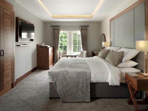 皇家滕布里奇韦尔斯壹华威公园酒店的一间卧室配有一张大床和电视