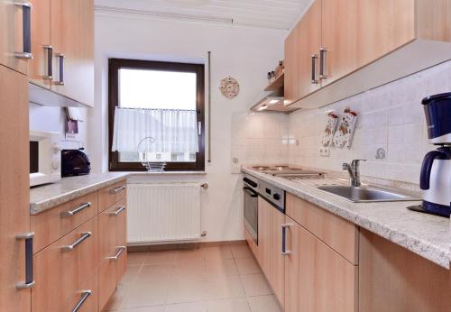 迪布利希Ferienwohnung Brinkmann 4**** mit Moselblick的厨房配有木制橱柜、水槽和窗户。