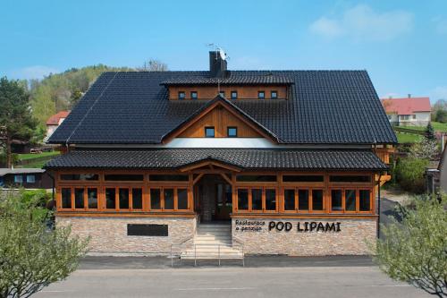 MetyloviceRestaurace a penzion Pod Lipami Metylovice的一座大型木制建筑,设有黑色屋顶