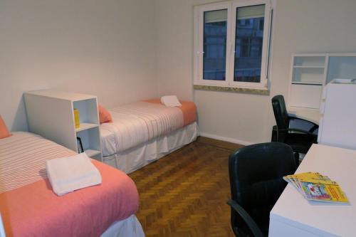 里斯本拜罗度假公寓的客房设有两张床和一张带椅子的桌子。