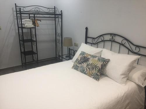 托莱多Apartamento Tolaitola的卧室配有一张白色的床、黑色床头板和枕头。