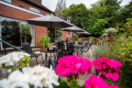 伯明翰Westbourne Lodge的户外庭院配有桌椅和粉红色的鲜花