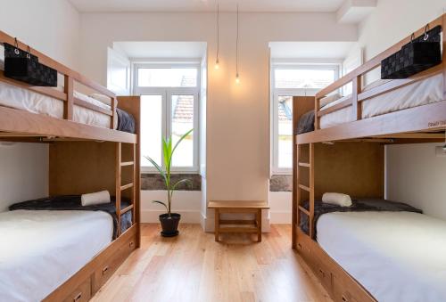 蓬塔德尔加达Pé Direito的客房铺有木地板,设有两张双层床和窗户。