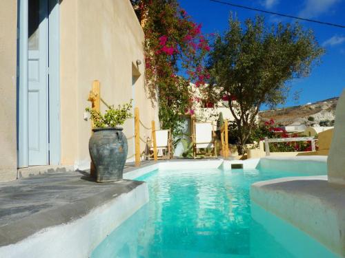 安坡里奥圣托里尼巴巴罗萨套房度假屋的一座游泳池,在建筑物的一侧有一个花瓶