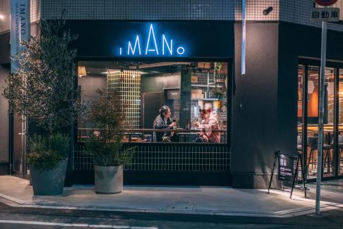 大阪IMANO OSAKA SHINSAIBASHI HOSTEL的夜间城市街道上的一间马诺餐厅