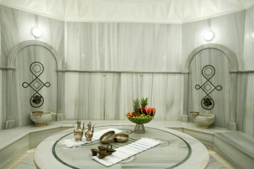 伊斯坦布尔西瓦希尔会议中心大酒店的一间白色的房间,配有一张桌子和一碗水果
