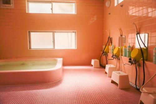 轻井泽轻井泽佐藤奴库利旅馆的大型橙色浴室设有浴缸和窗户