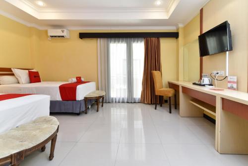 登巴萨RedDoorz Plus near Mall Bali Galeria 2的酒店客房配有两张床和一张书桌