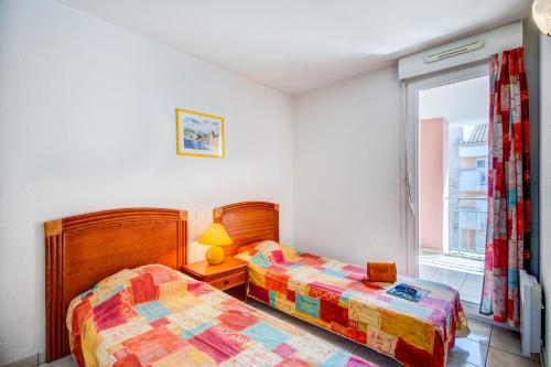 圣艾格夫Vacancéole - Les Calanques Du Parc的一间卧室设有两张床和窗户。