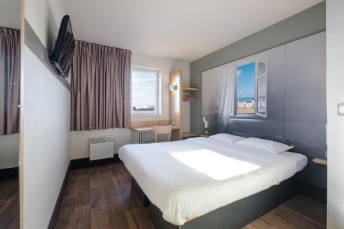 加来B&B HOTEL Calais Centre St Pierre的一间设有大床和窗户的酒店客房