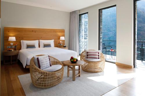瑞诗凯诗Taj Rishikesh Resort & Spa Uttarakhand的一间卧室配有一张床、两把椅子和一张桌子
