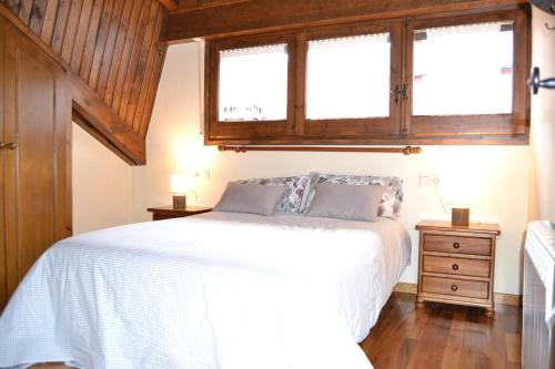 贝尔维尔德赛当亚Bonito ático en Bellver de Cerdanya的卧室配有白色的床和2扇窗户。