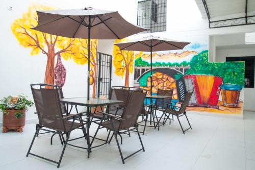巴耶杜帕尔Aparta Hotel El Cacique Upar的画前的桌椅和遮阳伞