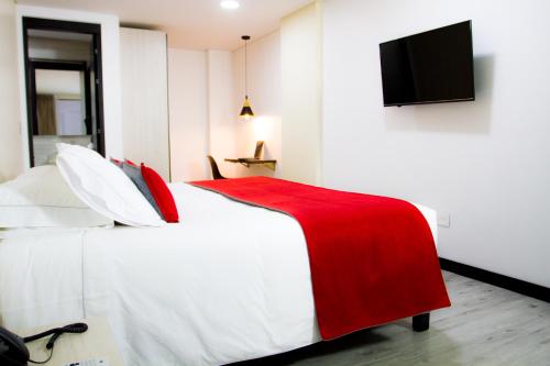 波哥大Hotel WLH Bogota - White Lighthouse的一间卧室配有一张带红色毯子的床和一台平面电视。