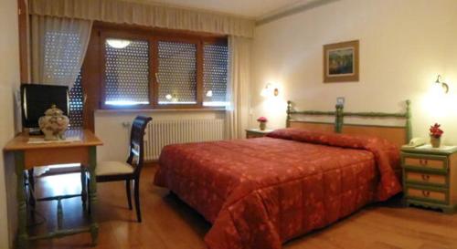 坎皮泰洛迪法萨费德拉公园酒店的一间卧室配有红色的床、一张书桌和一张书桌
