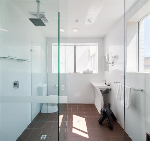 悉尼57号酒店的一间带玻璃淋浴和水槽的浴室