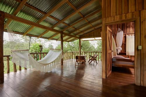比加瓜Finca Amistad Cacao Lodge的一个带吊床的门廊、一间卧室和一张床