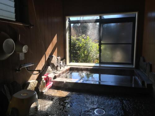 由布市山荘 紗羅樹 Syaranoki的一间带水槽的浴室和一个带水的窗户
