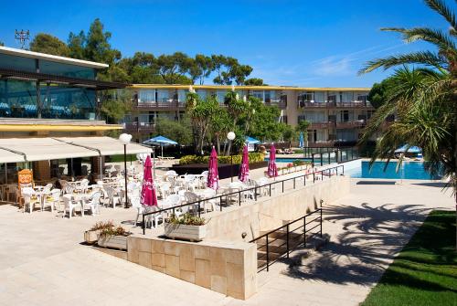 普拉加德阿罗科姆塔特圣霍尔迪公寓式酒店的一个带游泳池、桌子和粉红色遮阳伞的度假村