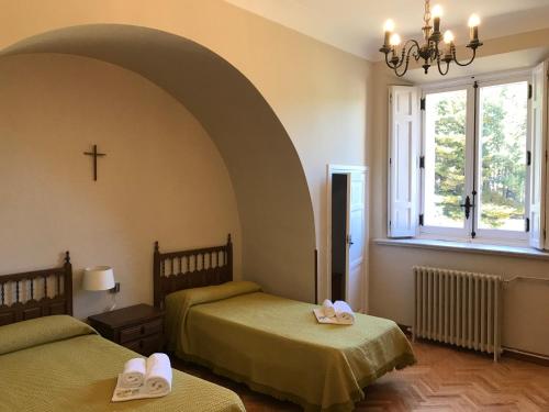 圣洛伦索-德埃斯科里亚尔豪斯彼得瑞亚圣克鲁兹旅馆的卧室配有两张床,墙上有一个十字架