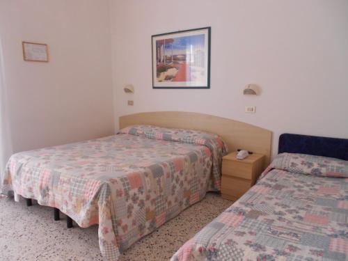 里米尼拉古娜布鲁酒店的酒店客房设有两张床和床头柜。