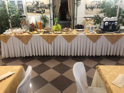 皮昂比诺Antico Hotel Moderno的一张桌子,上面有食物,上面有白色的椅子