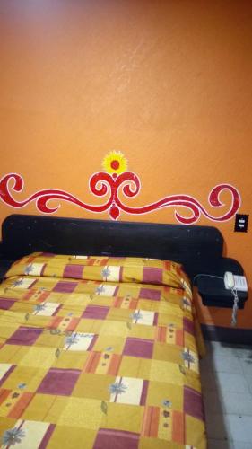 墨西哥城Hotel Recreo的墙上一张红色和黄色被子的床