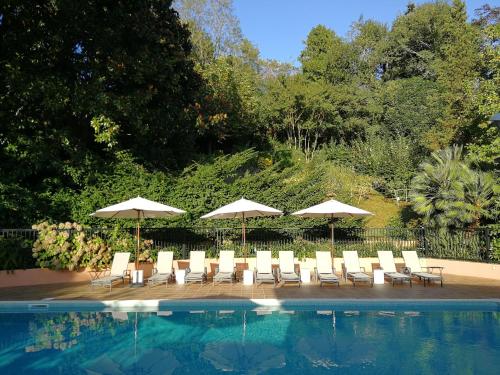 圣让-德吕兹尚塔克高尔夫康体酒店的一组椅子和遮阳伞,位于游泳池旁