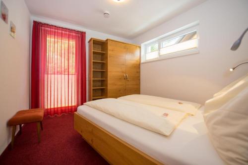 魏森湖Ferienwohnungen Mitterer的一间卧室设有一张床和一个红色的窗户