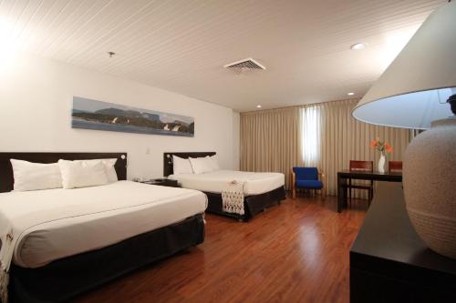 加拉加斯Hotel CCT Caracas的酒店客房配有两张床和一张书桌