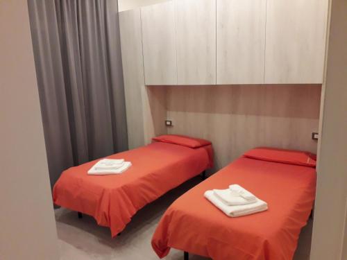 奥梅尼亚La CasaLina的宿舍间的两张床,配有红色床单和白色毛巾