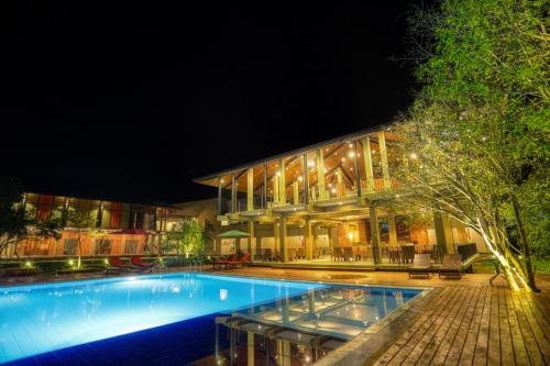 丹不拉Tropical Life Resort and Spa的一座游泳池,在晚上在建筑物前