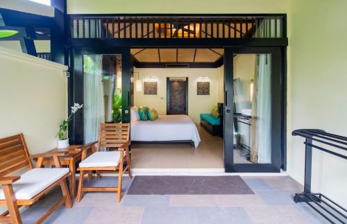 芭东海滩Impiana Beach Front Resort Patong, Phuket的带床和椅子的房间以及一间卧室