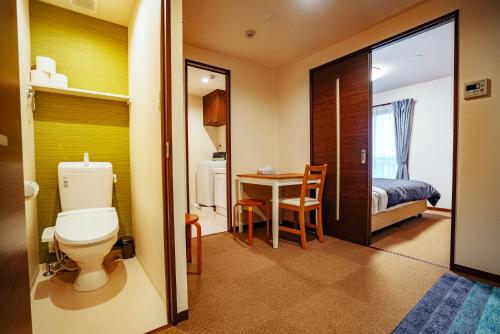 京都Ben's Guesthouse Kyoto的一间带卫生间的浴室和一张桌子及一张床
