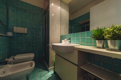 都灵Accogliente monolocale alla Gran Madre的浴室设有水槽、卫生间和绿色瓷砖。