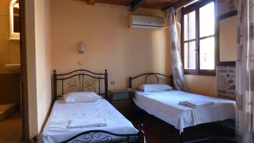 干尼亚凯多尼亚客房酒店的一间卧室设有两张床和窗户。