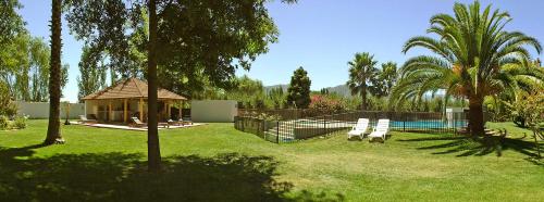 圣克鲁兹La Perla Hotel的后院设有游泳池、凉亭和两把椅子