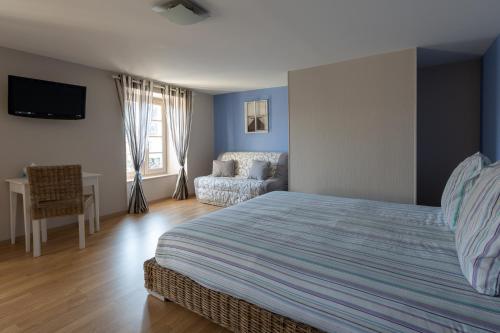 Saint-Martin-la-MéanneLes Voyageurs的一间卧室配有一张床、一把椅子和一张沙发