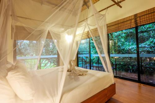考索Anurak Community Lodge - SHA Plus的卧室配有白色天蓬床和窗户
