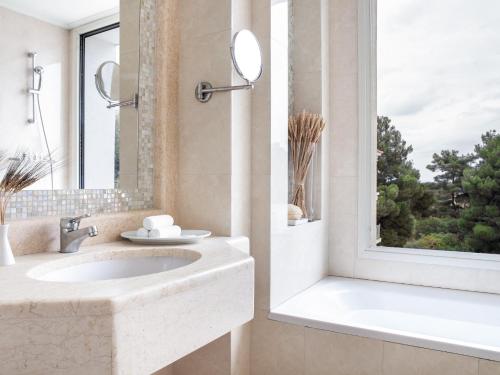 拉里萨Grecotel Larissa Imperial的一间带水槽和浴缸的浴室以及窗户。