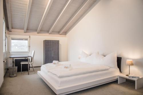 龙疆House Lakeside – GriwaRent AG的白色的卧室配有白色的床和钢琴