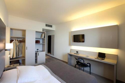 阿罗纳花园酒店的一间卧室配有一张床和一张书桌及电视