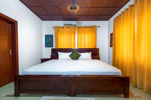 库马西Okumah Hotel的一间卧室配有带橙色窗帘的大床