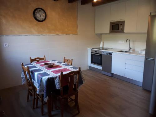 米瑟斯APARTAMENTOS CAMINO SANTO TORIBIO的厨房配有桌椅和墙上的时钟