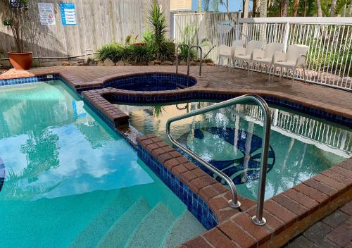 黄金海岸奥特雷格伯利度假村的游泳池设有楼梯,通往带椅子的庭院