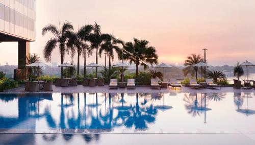 仰光仰光梅里亚酒店的酒店游泳池拥有棕榈树和遮阳伞