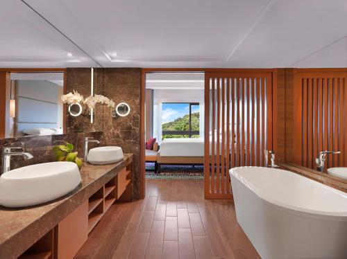关丹关丹凯悦酒店的一间带两个盥洗盆和浴缸的浴室以及一间卧室