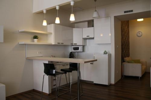 布达佩斯Arany Janos Apartman的厨房配有白色橱柜、柜台和凳子