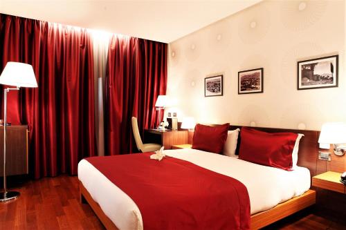 地拉那地拉那国际酒店及会议中心的一间卧室配有一张带红色窗帘的大床